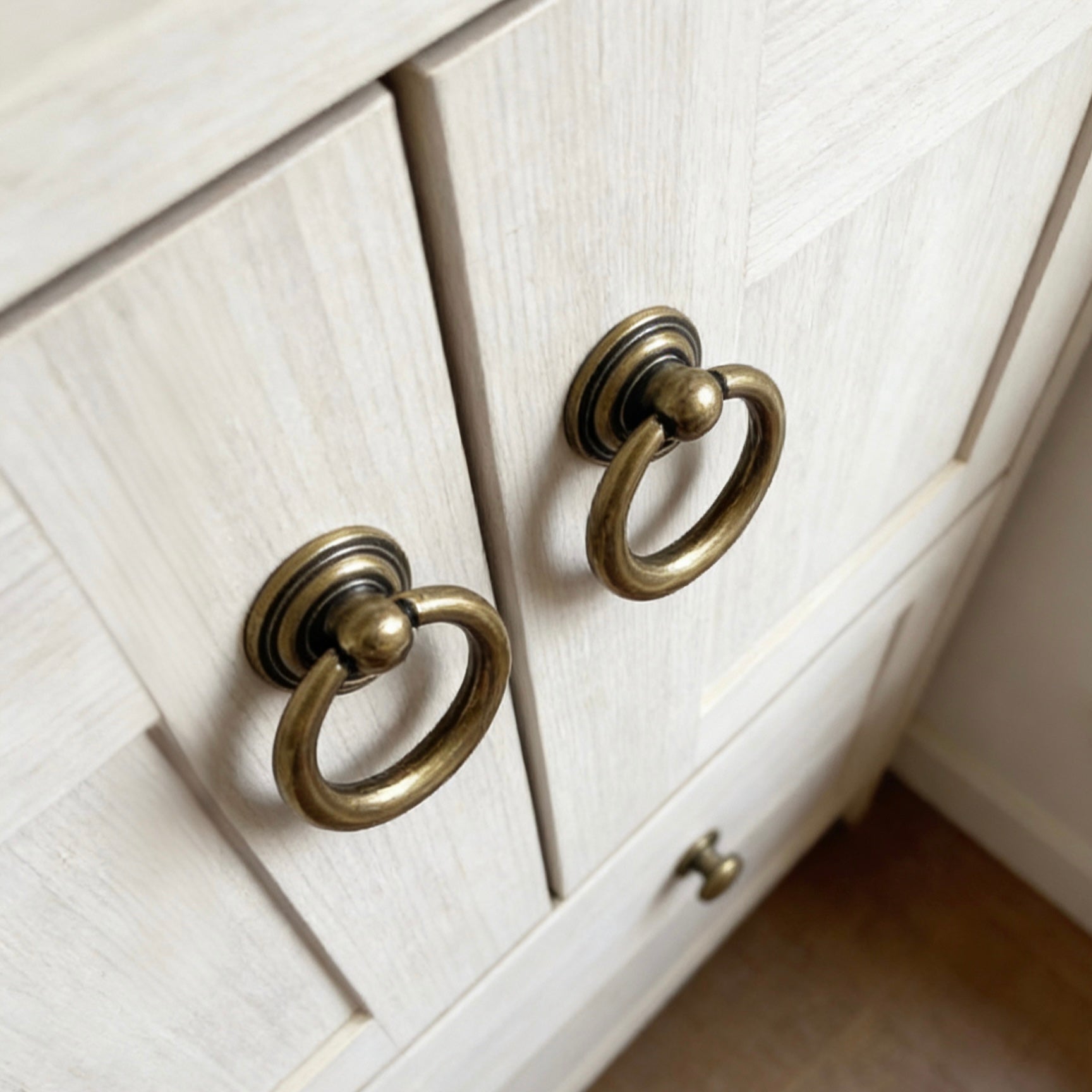 Close-up of a white cabinet with brass ring pulls