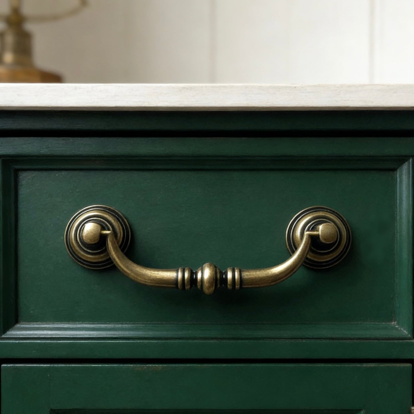 Green cabinet with brass swing bail handles on a neutral background