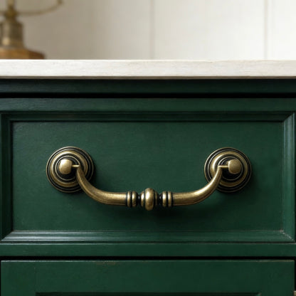 Green cabinet with brass swing bail handles on a neutral background