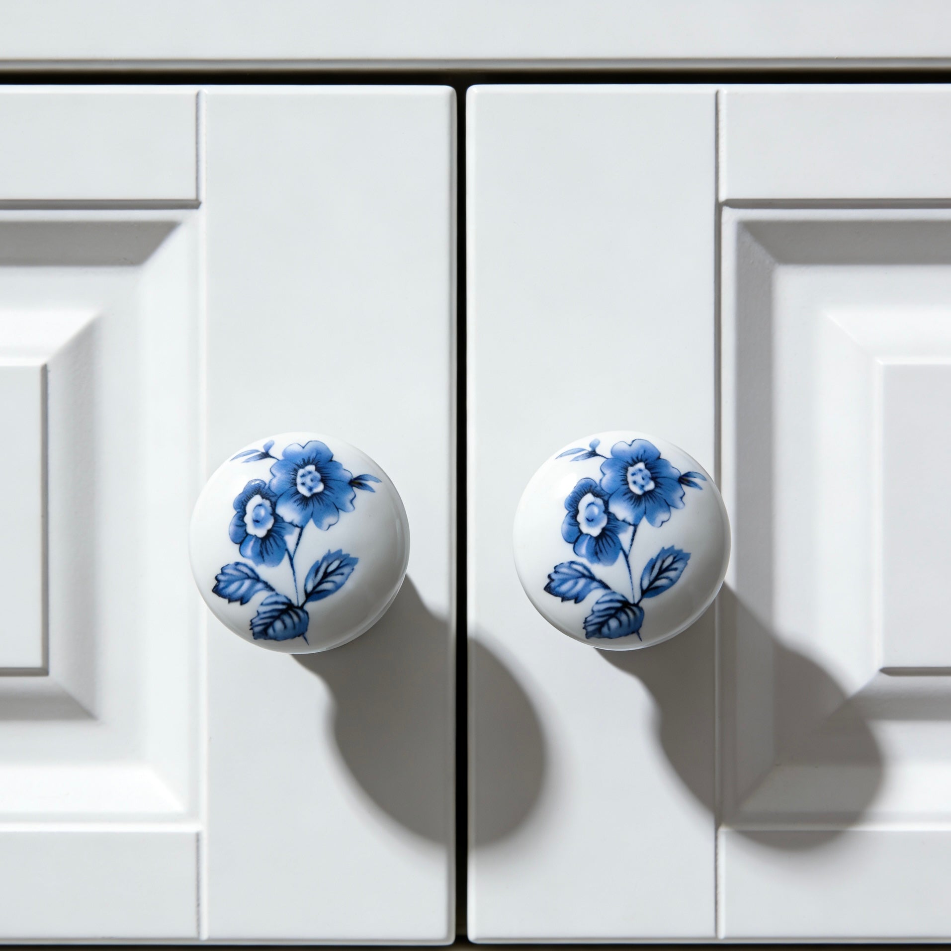 White cabinet doors with blue floral knobs on a white background