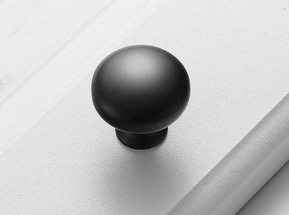 Black cabinet knob on a white textured surface
