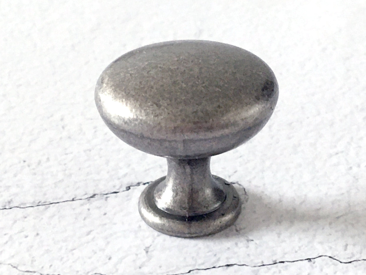 Pewter cabinet knob on a textured white background