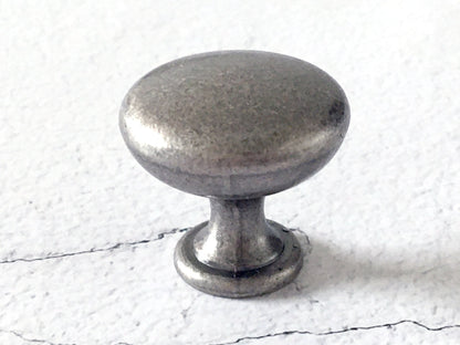 Pewter cabinet knob on a textured white background