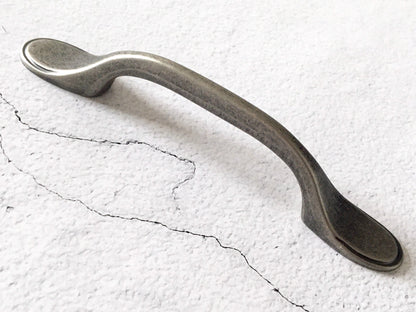 Pewter cabinet handle on a textured white surface
