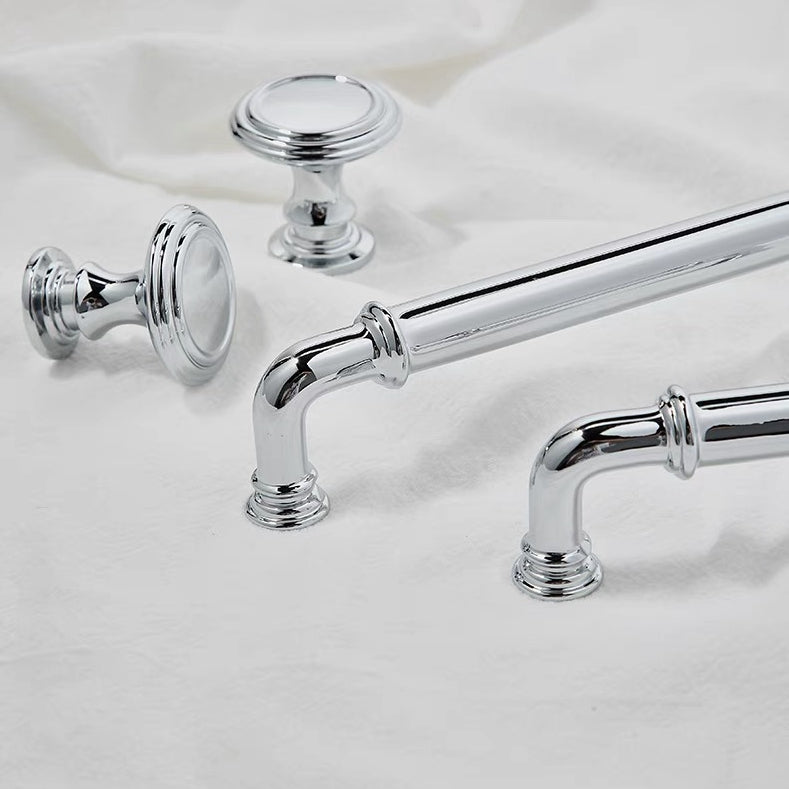 Chrome cabinet handles and knobs on a white fabric background
