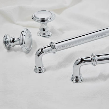 Chrome cabinet handles and knobs on a white fabric background