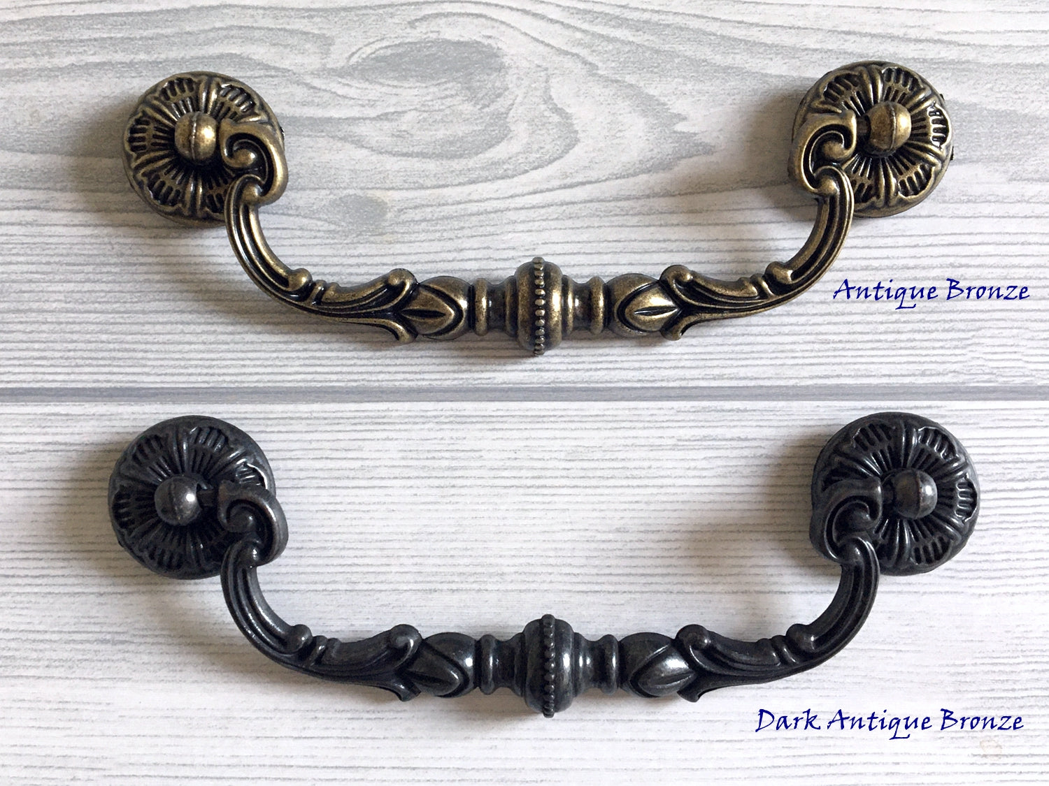 Two cabinet swing bail handles, one in antique bronze and one in dark antique bronze, on a light wooden surface.