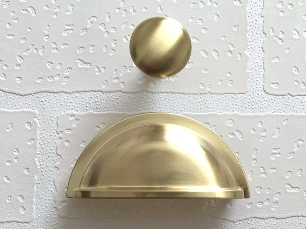 Gold cabinet knob and pull on a textured white surface