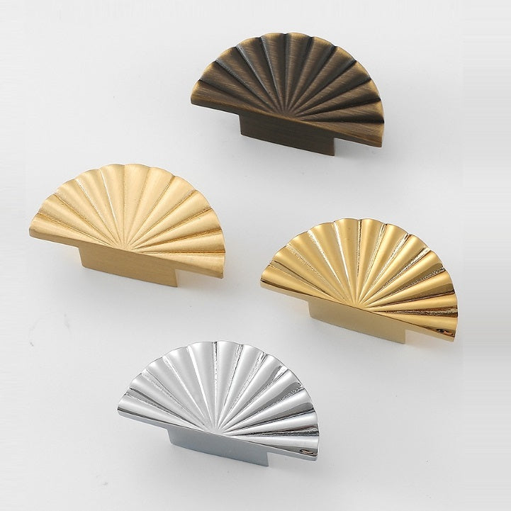 Set of four decorative sunburst half moon drawer knobs in gold, bronze, and silver on a white background