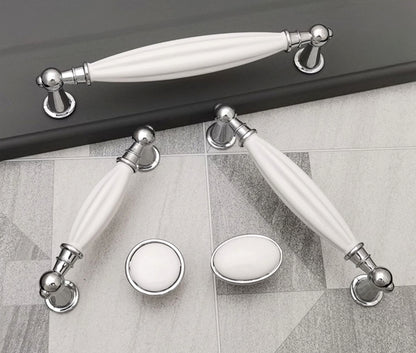 Set of white ceramic handles with silver metal accents on a tiled floor.