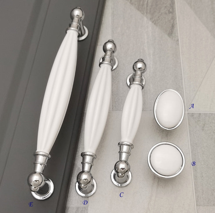 Set of white cabinet handles with silver hardware on a gray background