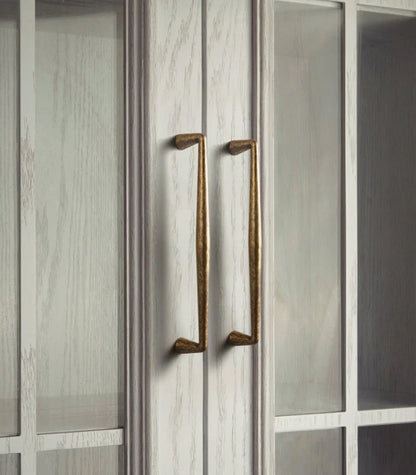 Close-up of rustic antique brass handles on a cabinet door.