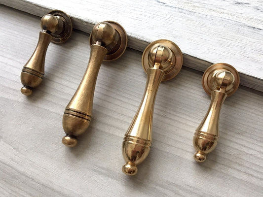 antique brass teardrop door handles on a wooden surface