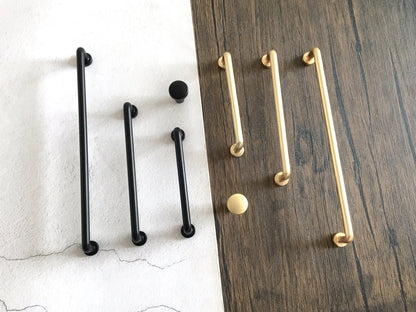 Set of black and gold cabinet bar handles on a wooden and white background
