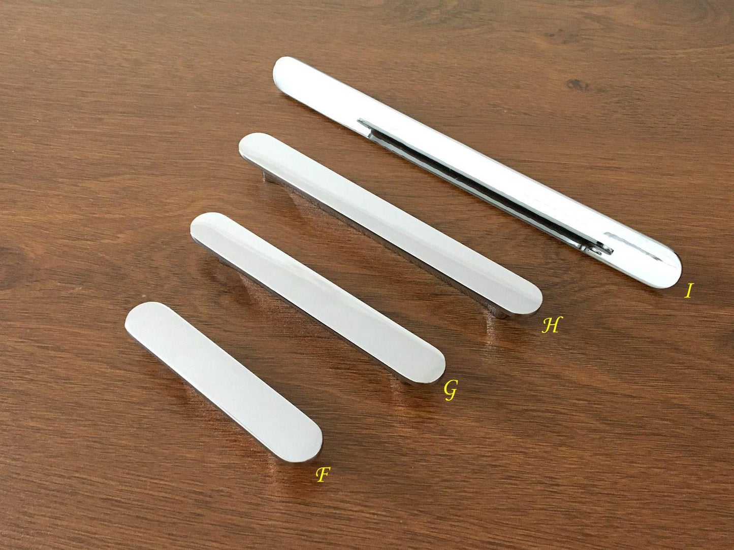 Set of streamlined silver kitchen handles  on a wooden surface