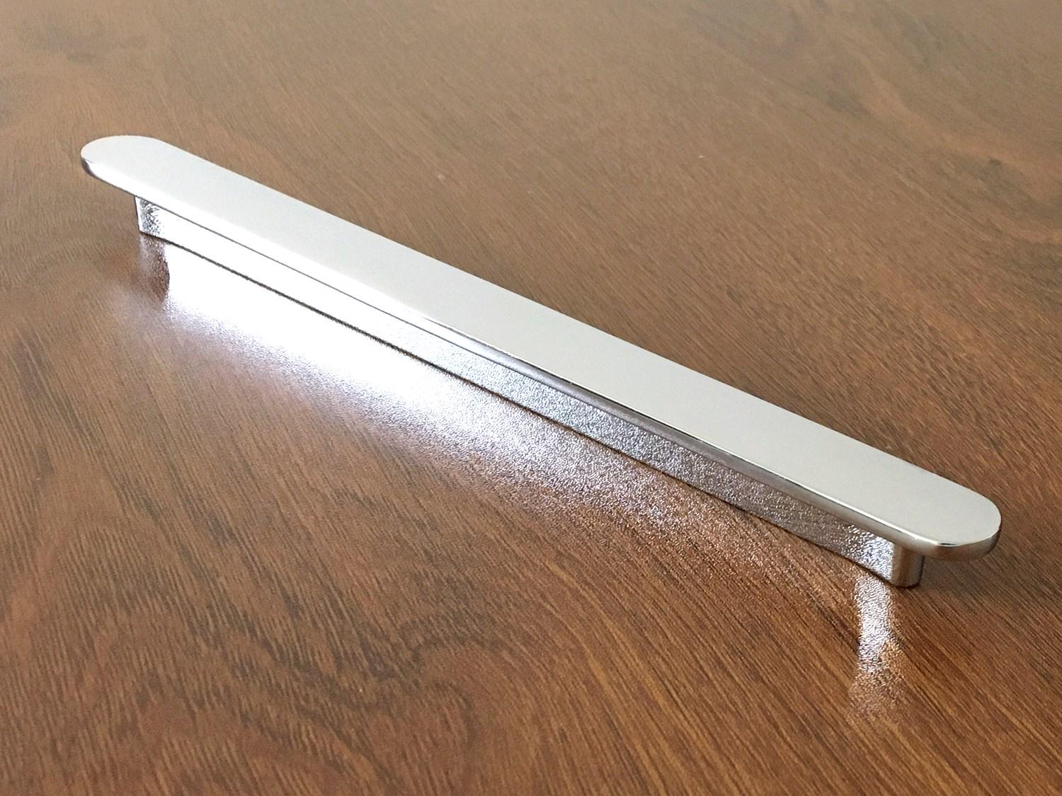 Metallic polished chrome handle on a wooden surface