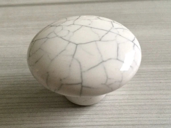 White ceramic knob with gray cracks on a textured surface