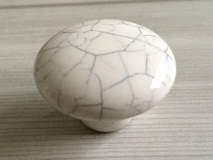 White ceramic knob with gray cracks on a textured surface
